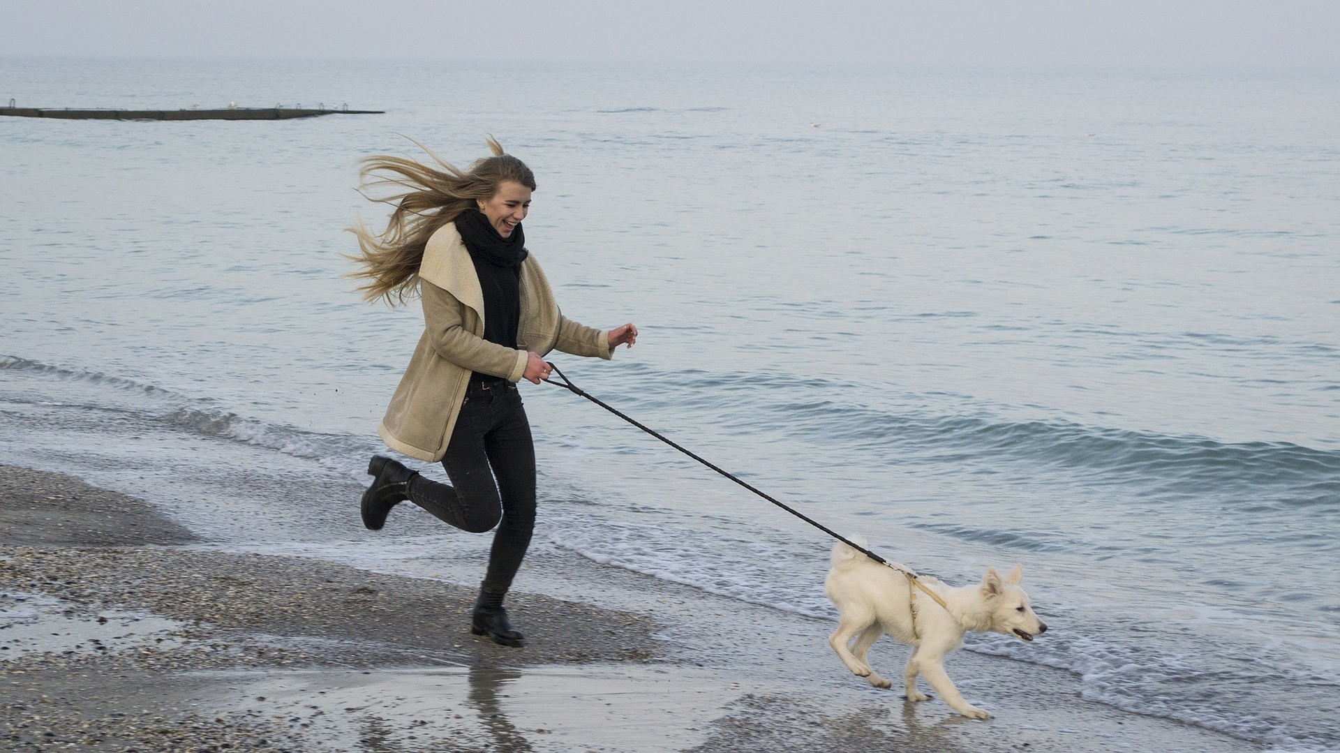 chica corriendo por la playa con perro para bajar peso haciendo ejercicio